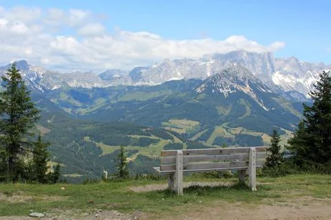 Bench at the top of the mountain overlooking the forest and mountain peaks Stock Photos