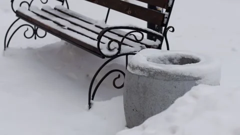 A bench under the snow with a trash can in the city in winter, slow motion Stock Footage 291776977