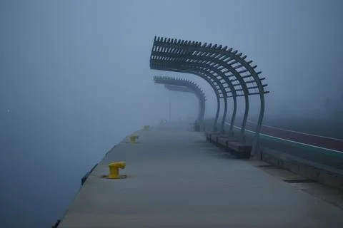 Benches along empty pier during heavy fog Stock Photos