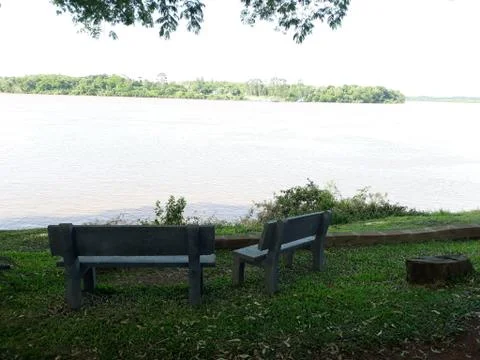 Benchs facing the river, to sit and relax Stock Photos