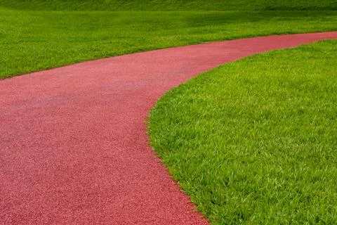 The bend of a red plastic track in the grass in the park Foto stock