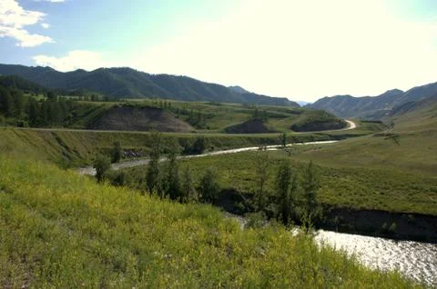 The bend of a river bed flowing through a valley surrounded by mountains. Stock Photos