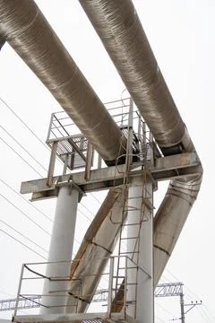 Bending of two thick pipes of the heating system on a high support with a met Stock Photos