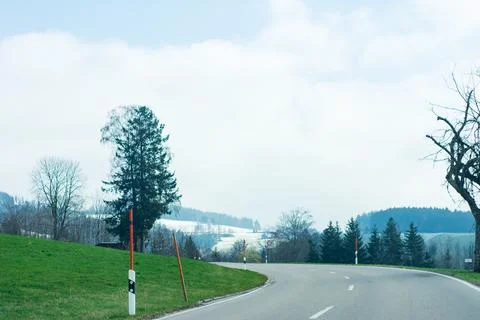 Beneath a canopy of soft clouds, a gentle curve in the road leads through vib Stock Photos