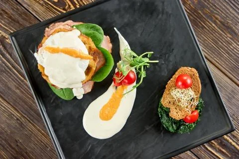 Benedict with ham on black rectangle plate. Stock Photos