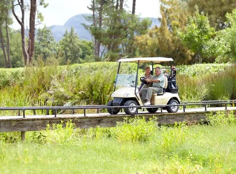 The benefits of being a club member. A mature couple driving a golf cart to Stock Photos