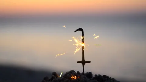 Bengal fire sparkler in shape of number 1 one burning sparkling on sand beach Stock Footage 247018904