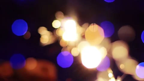 Bengal fire with sparks in hand on a background of blue New Years lights on Stock Footage 293683358