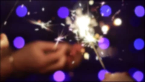 Bengal fire with sparks in hand on a background of blue New Years lights on Stock Footage 293683553