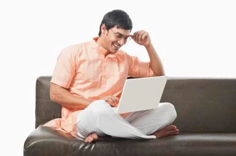Bengali man using a laptop on the couch Stockfoto's