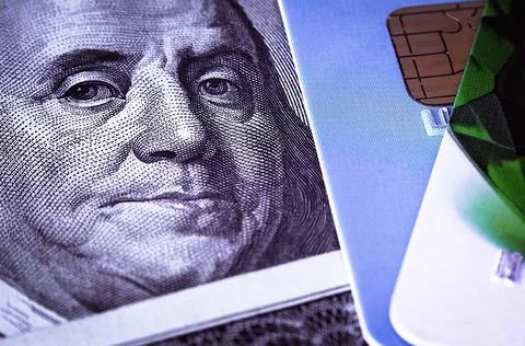 Benjamin Franklin's face on a hundred-dollar bill next to a credit card. Clos Stock Photos