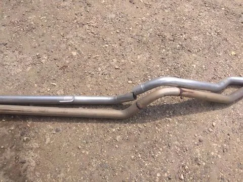 A bent pipe is laying on the ground. Stock Photos