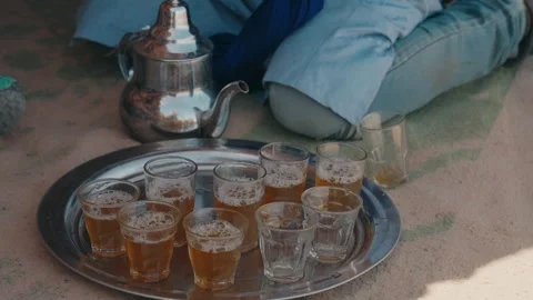Berber man serving mint tea glasses on silver tray inside cave dwelling Morocco 動画素材 334515374