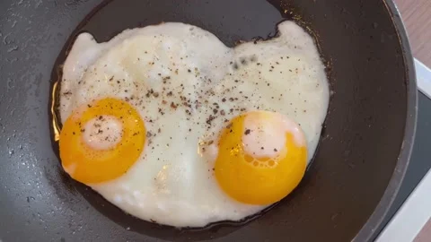 Berlin: Cooking two fried eggs (sunny side up) in a pan with oil, 4K Stock Footage 196859144