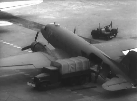 BERLIN, GERMANY - 1948: Apron loading - Covered truck loads transport aircraft Stock Footage 344495378