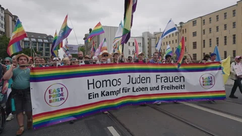 Berlin, Germany - July 26, 2025: LGBT activists carry rainbow banner and flags Stock Footage 346239644