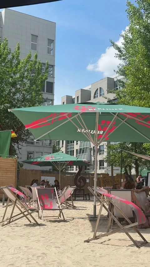 Berlin, Germany - May 23, 2026 - an urban beach bar scene displaying a green Stock Footage 339090116