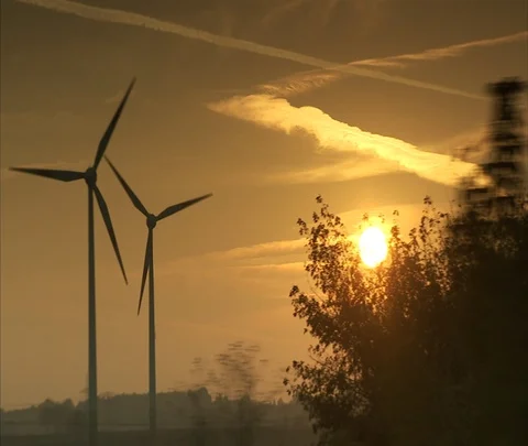 Berlin, Germany; tracking shot past wind turbines slowly turning with amber sky Stock Footage 86743252