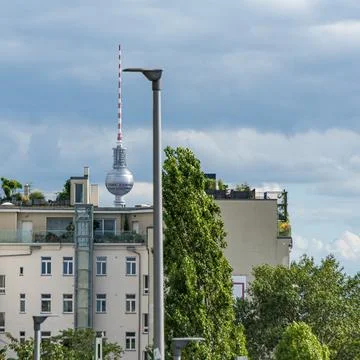 Berlin TV Tower behind rooftops and lampposts, cloudy sky 写真素材