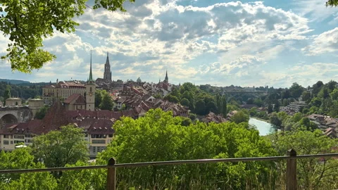 Bern old town rises above trees beside the winding Aare River in clear daylight Stock Footage 345235232