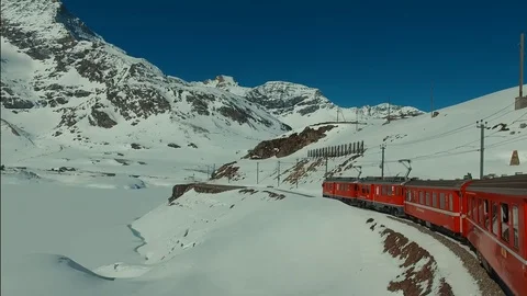 Bernina Express red train ascends to the Bernina Pass, glacier and Piz Bernina Stock Footage 74063375