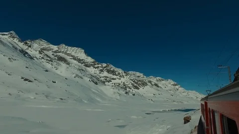 Bernina Express red train ascends to the Bernina Pass, glacier and Piz Bernina Stock Footage 74063414