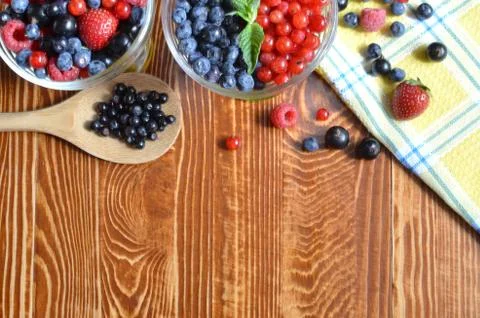 The berries are blue black and red on a brown wooden background Stock Photos