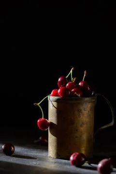 Berries of a cherry on branches in a bucket, rustic. Female hands hold branches. Stock Photos