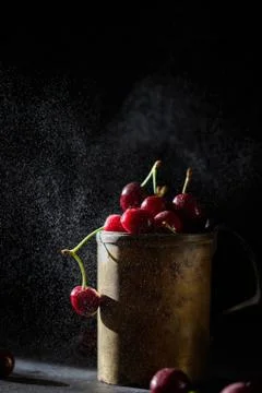 Berries of a cherry on branches in a bucket, rustic. Female hands hold branches. Stock Photos