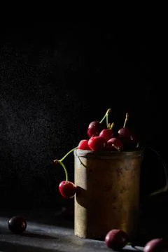 Berries of a cherry on branches in a bucket, rustic. Female hands hold branches. Stock Photos