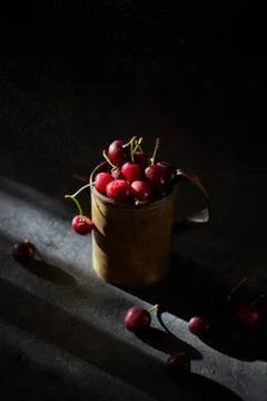 Berries of a cherry on branches in a bucket, rustic. Female hands hold branches. Stock Photos