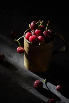 Berries of a cherry on branches in a bucket, rustic. Female hands hold branches. Stock Photos