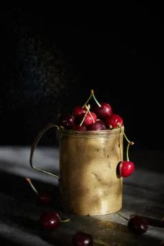 Berries of a cherry on branches in a bucket, rustic. Female hands hold branches. Stock Photos