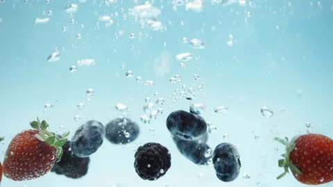 Berries fall into the water on blue background Stock Footage 107823171