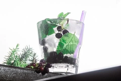 Berry cocktail, mint, ice in a rox glass on the edge of a bar counter white Stock Photos
