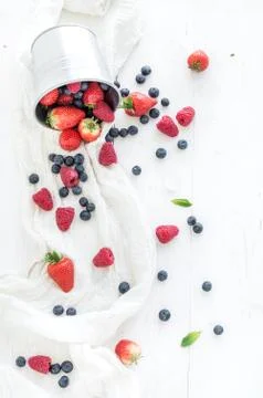 Berry frame with copy space on right. Metal bucket, strawberries, raspberries Stock Photos