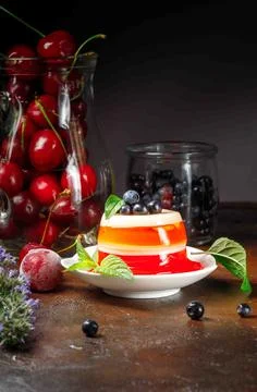 Berry jelly on a white plate, decorated with mint leaves. A glass jug with Stock Photos