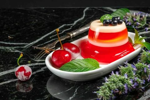Berry jelly on a white plate with frozen cherry berries and mint leaves Stock Photos