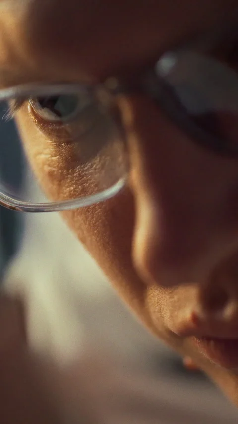 A bespectacled individual meticulously studies a tiny object on a cluttered Stock Footage 331528557