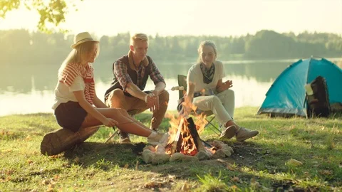Best friends cooking marshmallows on binfire on hike near the lake on summer Stock Footage 96242707