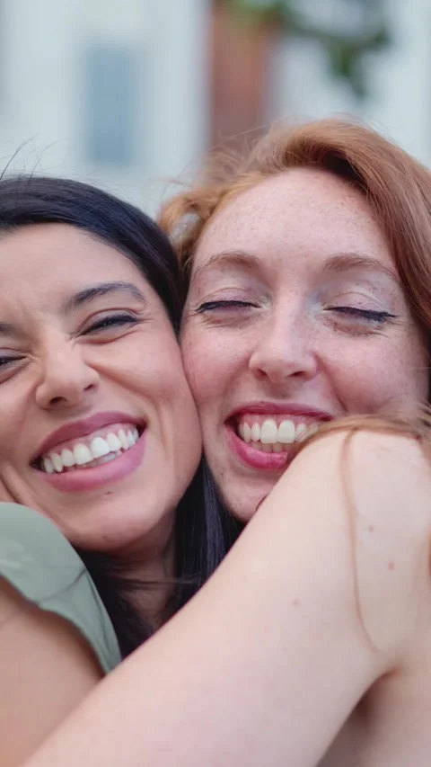 Best friends embracing while smiling in the street 스톡 동영상 242930989