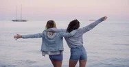 Best Friends Lifting Arms Up On Beach Watching Sunset Over Ocean Looking At Pink Stock Footage