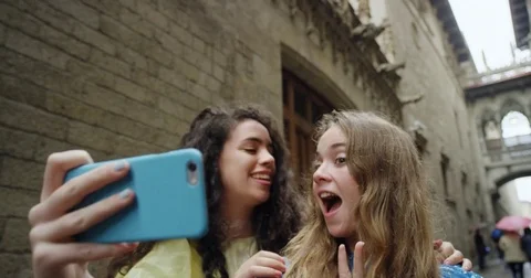 Best friends taking selfie using smartphone in Barcelona on Vacation in rainy Stock Footage 73343405