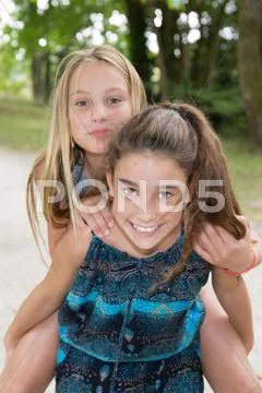 Best friends two girls, carrying friend piggyback Stock Photos