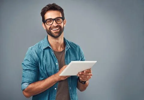 Best functionality ever. Studio shot of a handsome young man using a digital Stock Photos