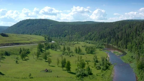 Between the road and river over beautiful meadows towards the forest. 스톡 동영상 111277143