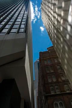 Between two skyscarpers old building behind bright blue sky. Stock Photos