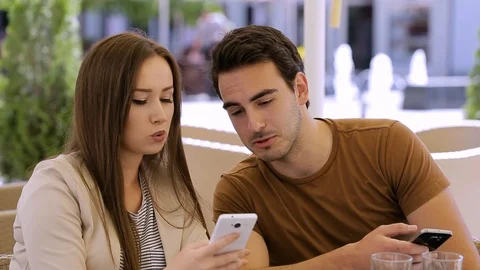 Beutiful couple sitting in caffe and typing on mobile phone Video stock 87393015