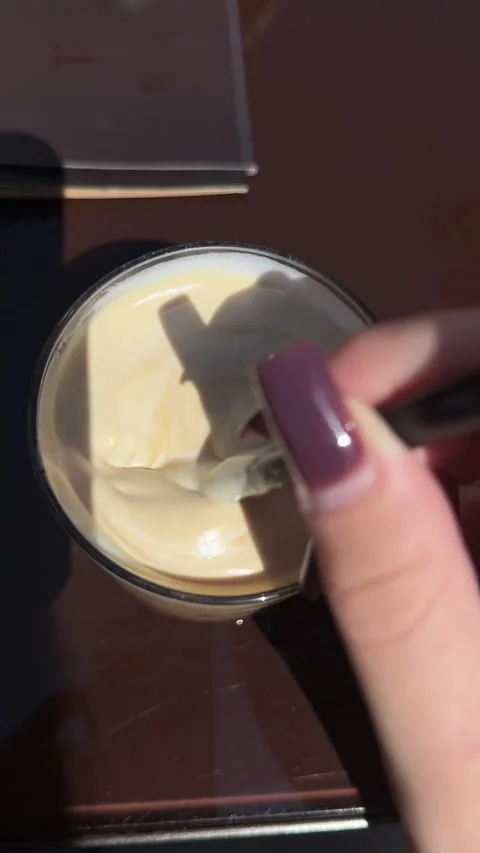 Beverage mixing process, a human hand stirring warm frothy milk foam and dark Stock Footage 334951443