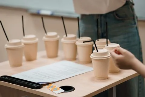 Beverage Sampling Event: Array of Paper Cups and Hand Reaching, Light Wood .. Fotos de archivo